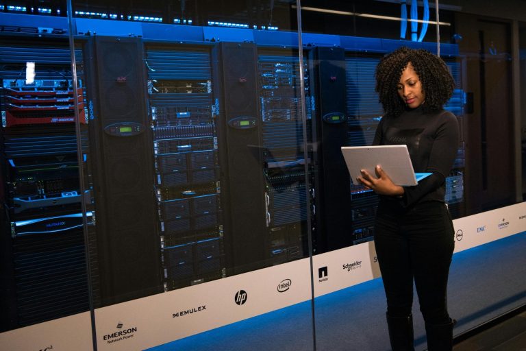 Lady standing with a laptop in front of a database system