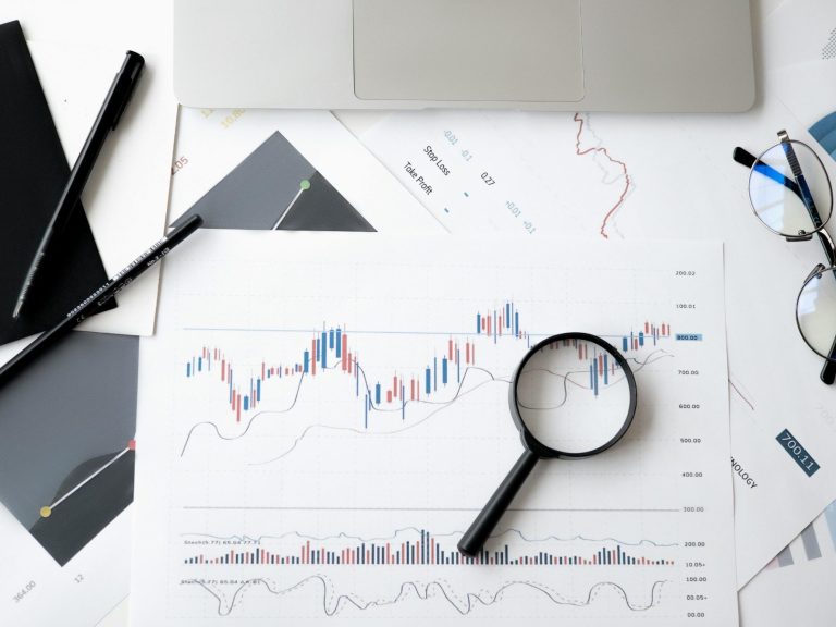 picture showing graphs, magnifier, stationery and glasses